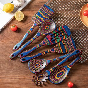 Seven-piece colorful Pakkawood kitchen utensil set arranged on a wooden countertop