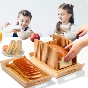 Foldable bamboo bread slicer with crumb tray as an adult cuts a loaf while bread slices rest on the separate tray