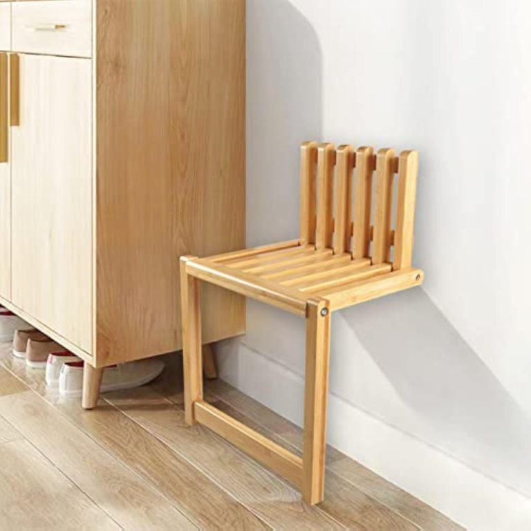 Wall mounted folding chair with a wood-toned slatted seat and back beside a shoe cabinet