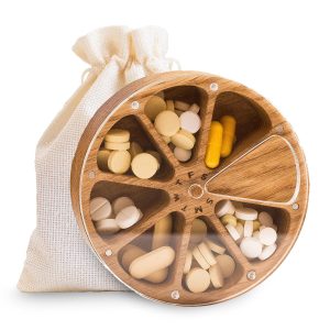 Round weekly pill organizer with seven filled compartments, a clear rotating lid and a fabric drawstring pouch