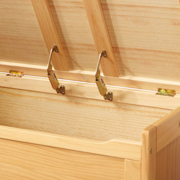 Close-up inside a wooden toy chest showing rear lid hinges and two metal support mechanisms