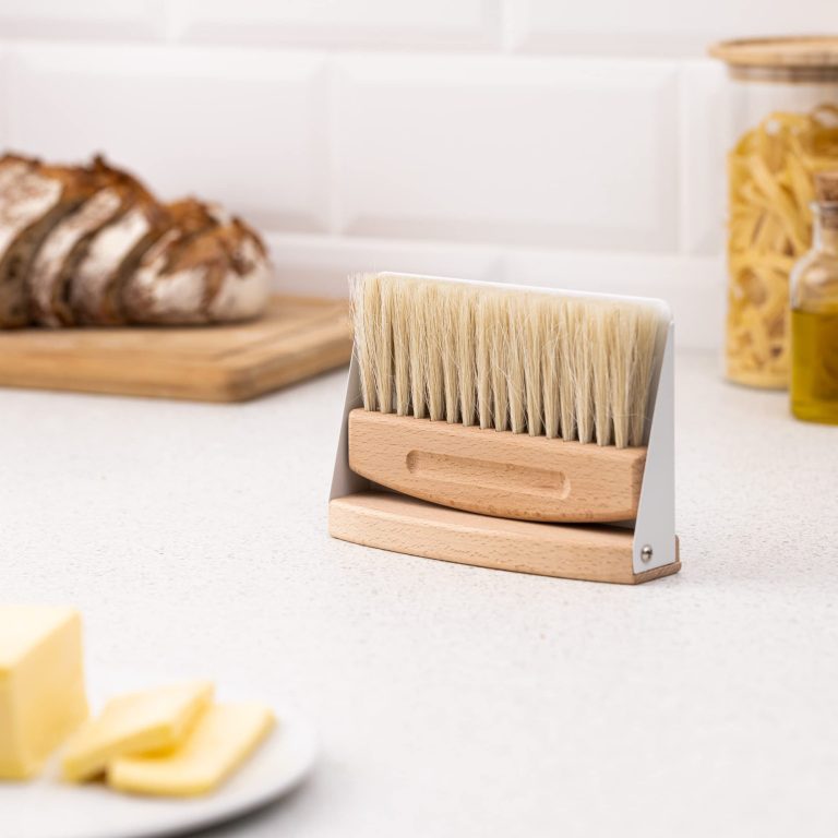 Compact wooden dustpan and brush set stored upright together on a kitchen counter