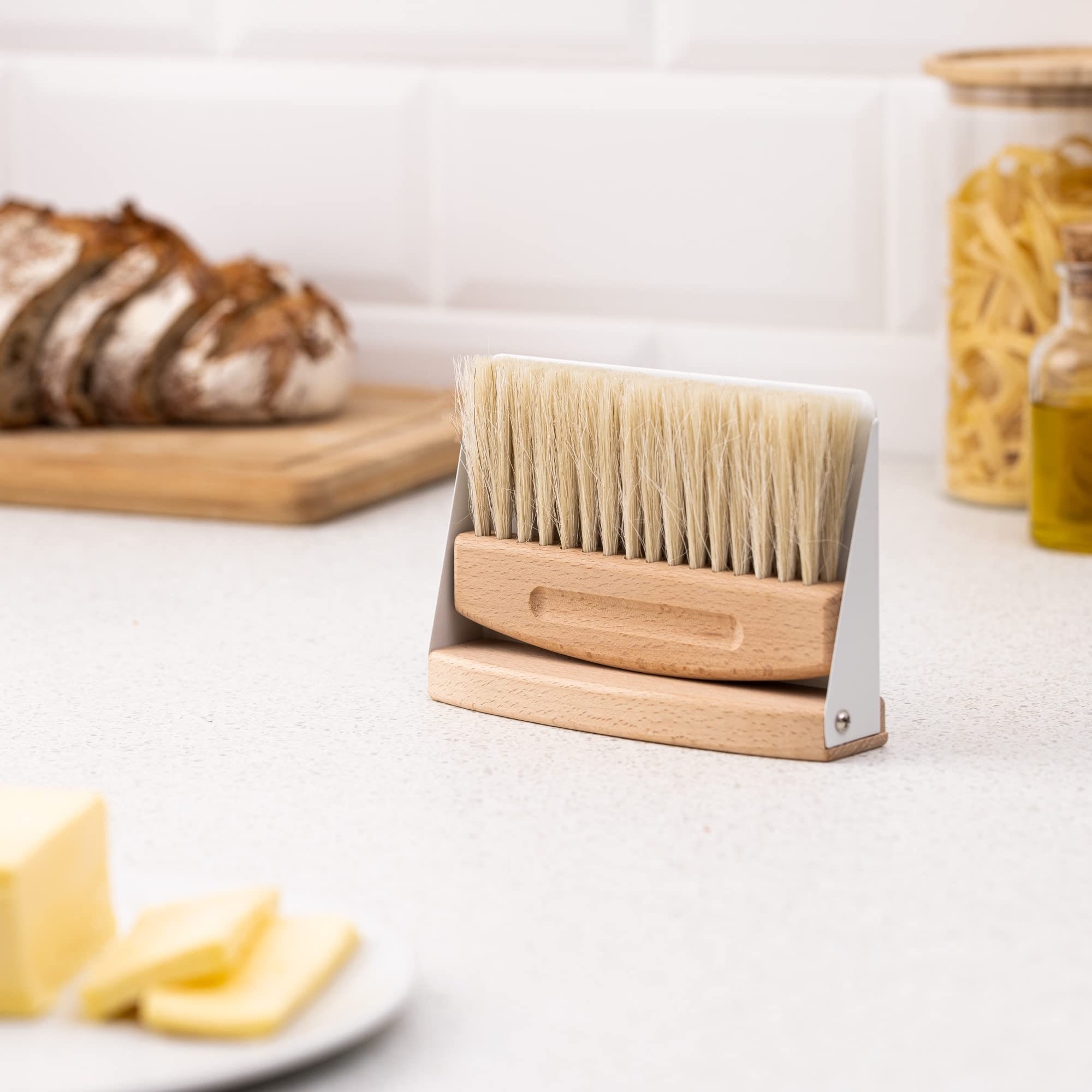 Compact wooden dustpan and brush set stored upright together on a kitchen counter