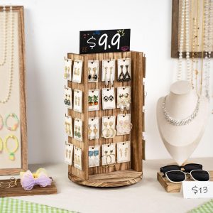 Wood jewelry display stand holding earring cards on a counter beside necklace and sunglasses displays