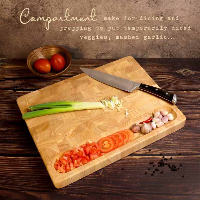 Reverse face of a wooden cutting board with a long recessed area holding chopped tomatoes and garlic