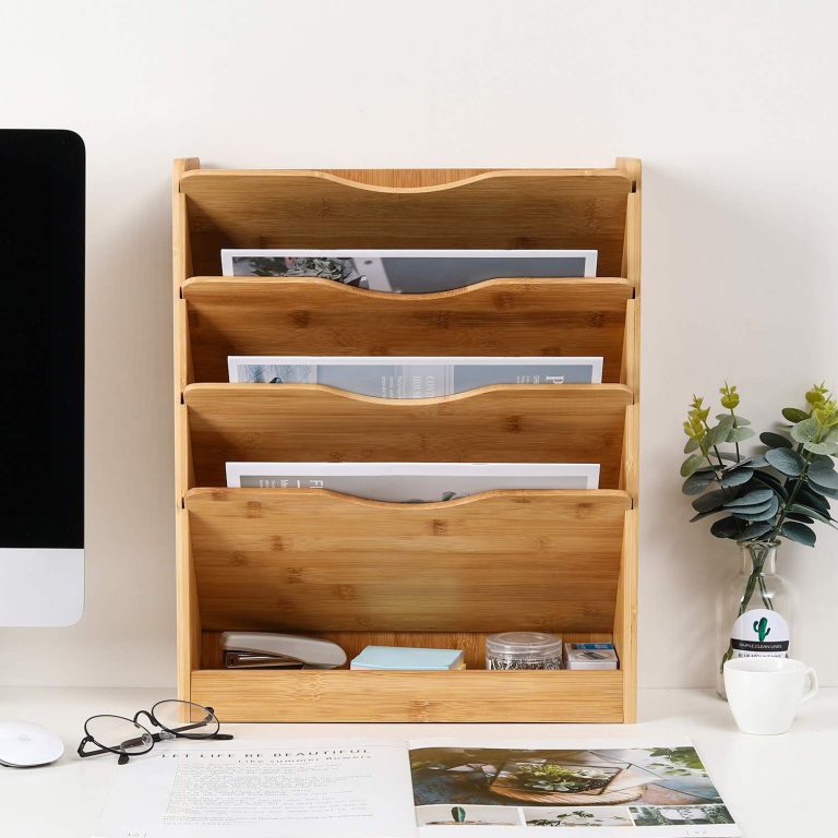Bamboo file organizer shown on a desk against a wall with papers in four pockets and stationery in the lower tray