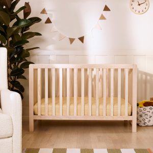 Wood crib with a pale frame and vertical slats in a nursery setting