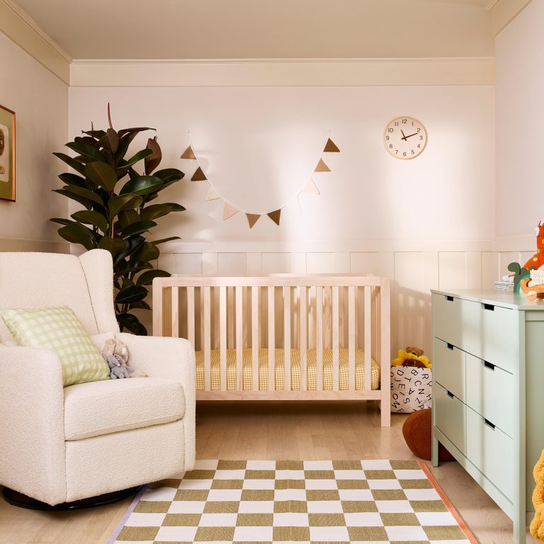 Wide nursery view with a pale wood crib, slatted sides and surrounding room furnishings