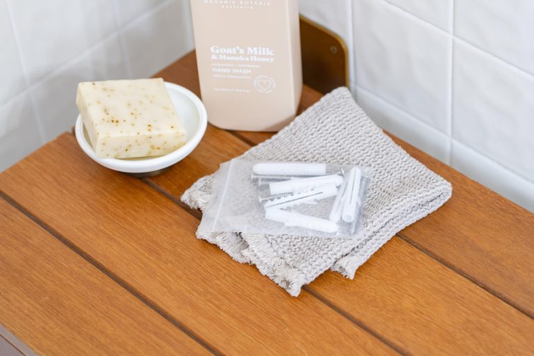 Close-up of the wooden folding shower seat's slatted surface with a cloth, soap dish and bath products