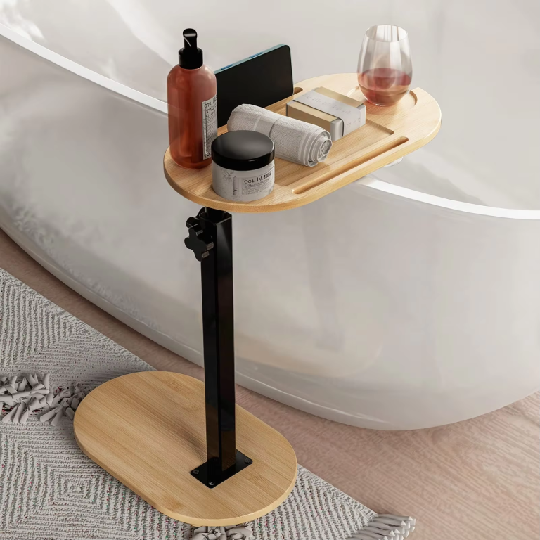 Freestanding bamboo bathtub tray with a rounded top, oval base, black metal post and hand knobs, pictured beside a bathtub