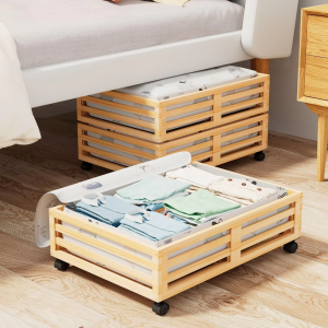 Bamboo underbed storage frames with horizontal slats and black wheels, pictured with printed fabric bags and folded clothing beside a bed