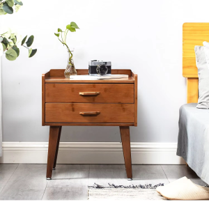 Two-drawer bedside table with brown wood-toned grain, raised back and side edges and four outward-angled legs beside a bed