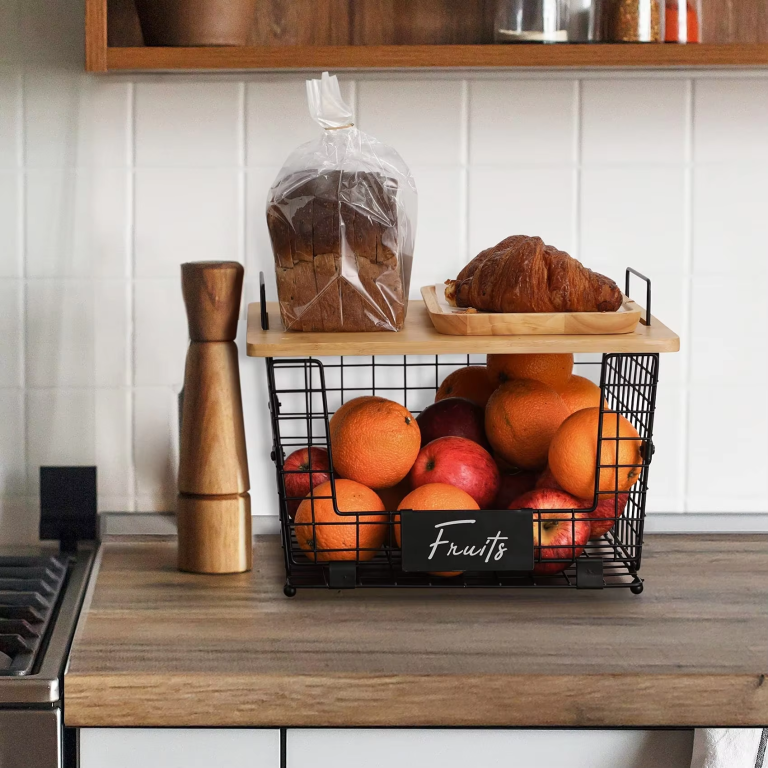 Black wire countertop organizer basket with a bamboo top, loop handles and a front label panel, pictured holding fruit on a kitchen counter