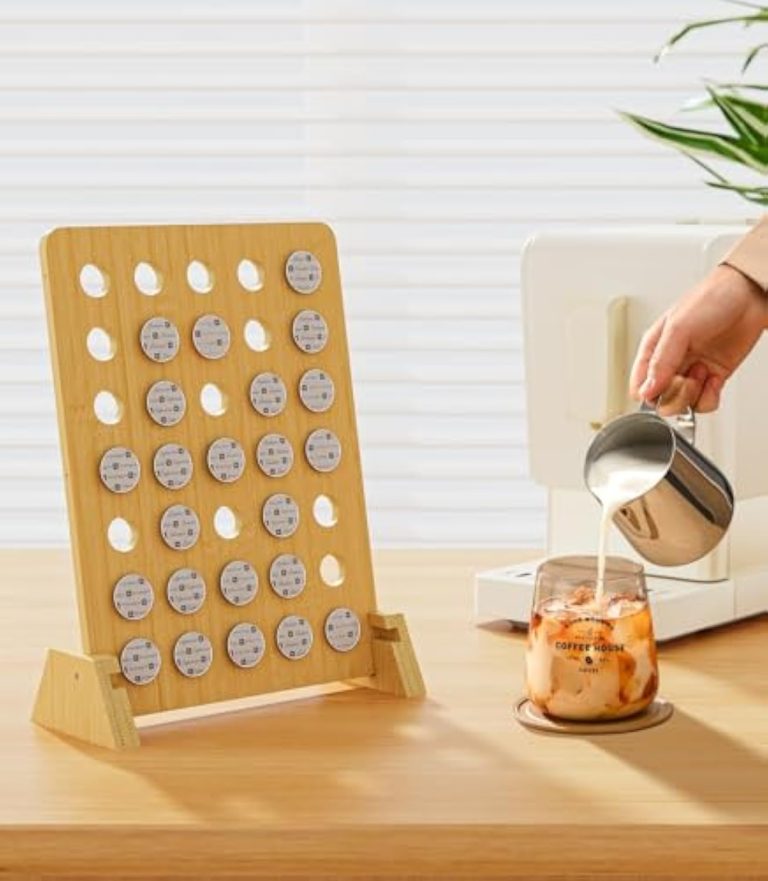 Upright bamboo coffee pod rack holding capsules beside a glass of iced coffee while milk is poured