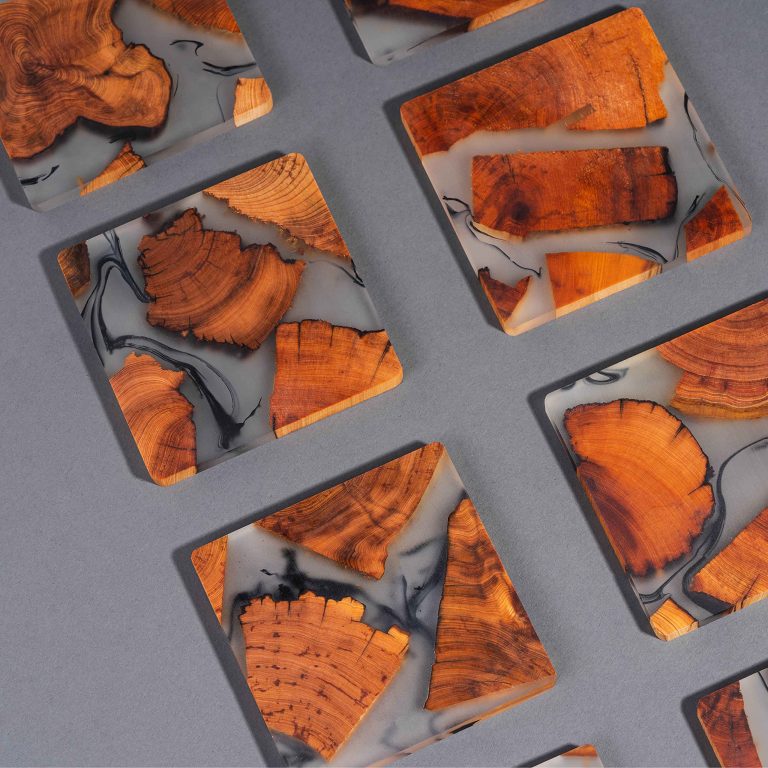 Resin coasters arranged on a gray background showing wood-grain sections and smoky black-veined patterns