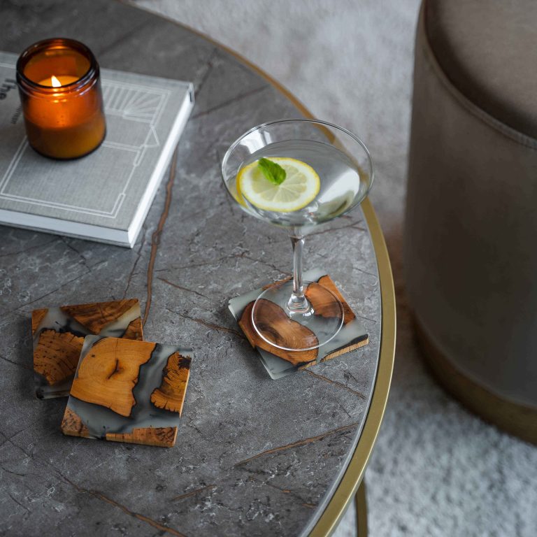 Stemmed glass resting on a wood and resin coaster beside two other coasters on a table