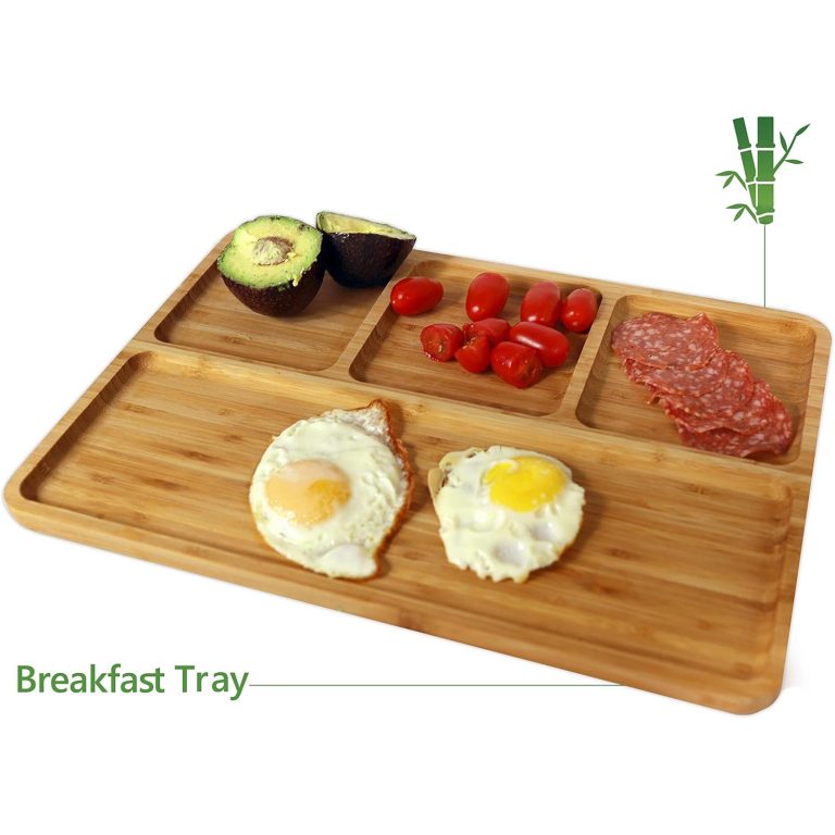 Four-compartment bamboo tray with eggs on toast in the long section and avocado, tomatoes and sliced meat in the smaller sections