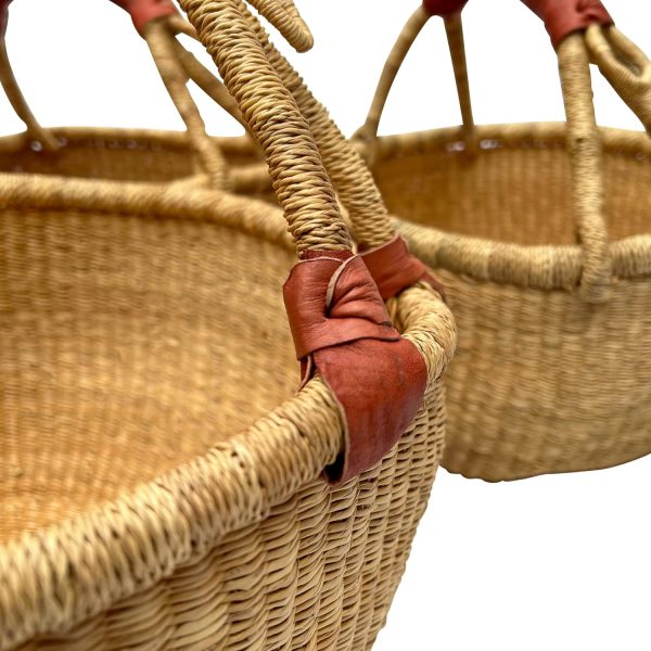 Close-up of woven basket handles with brown leather grip wrapping and tied leather attachments