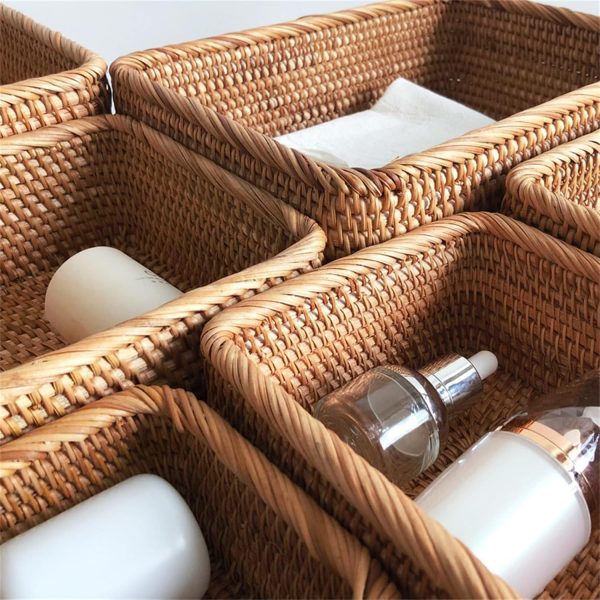 Close view of rectangular woven rattan baskets holding bottles and bathroom accessories beside a tissue box