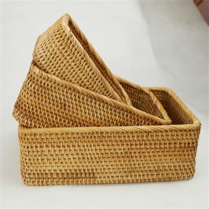 Three rectangular rattan storage baskets in graduated sizes arranged together to show the woven sides and nesting design