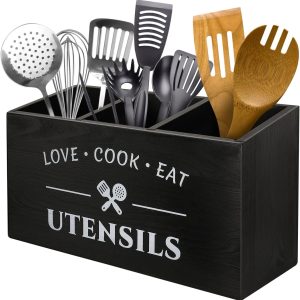 Black utensil storage holder with three compartments, white kitchen lettering and assorted cooking tools
