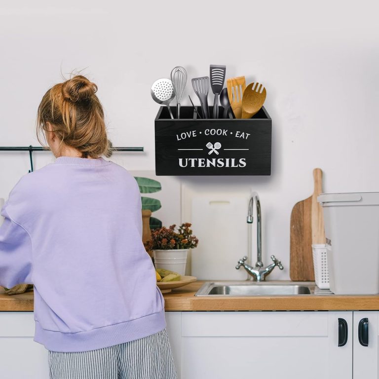 Black three-compartment utensil storage holder mounted on a kitchen wall above a sink