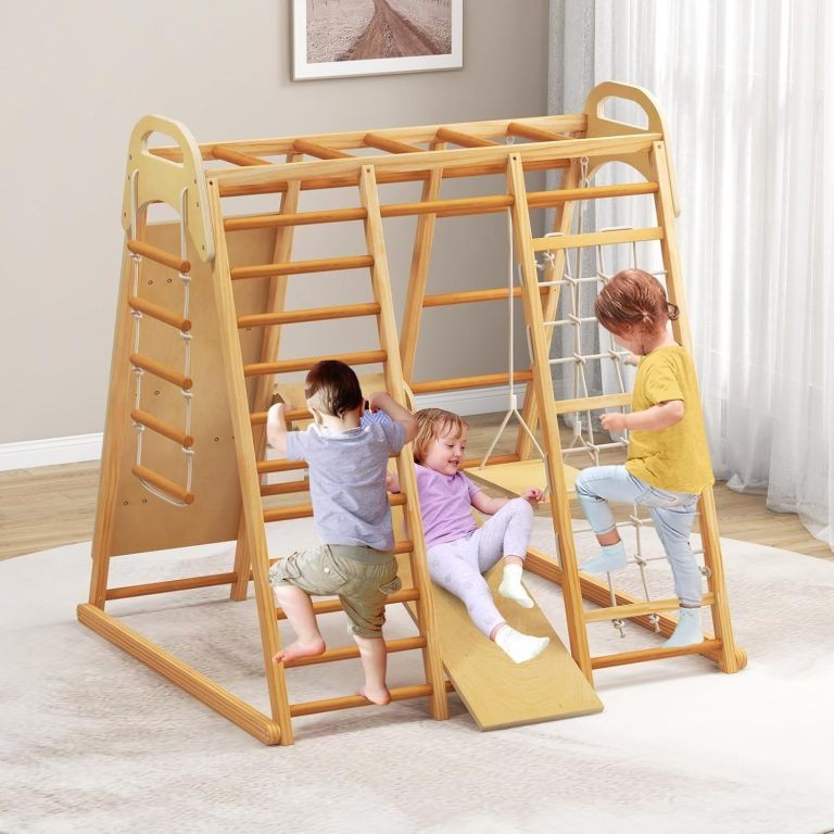 Alternate room view of a wooden indoor jungle gym with ladder rungs, a white rope net, a suspended flat seat and a smooth ramp face, pictured with children