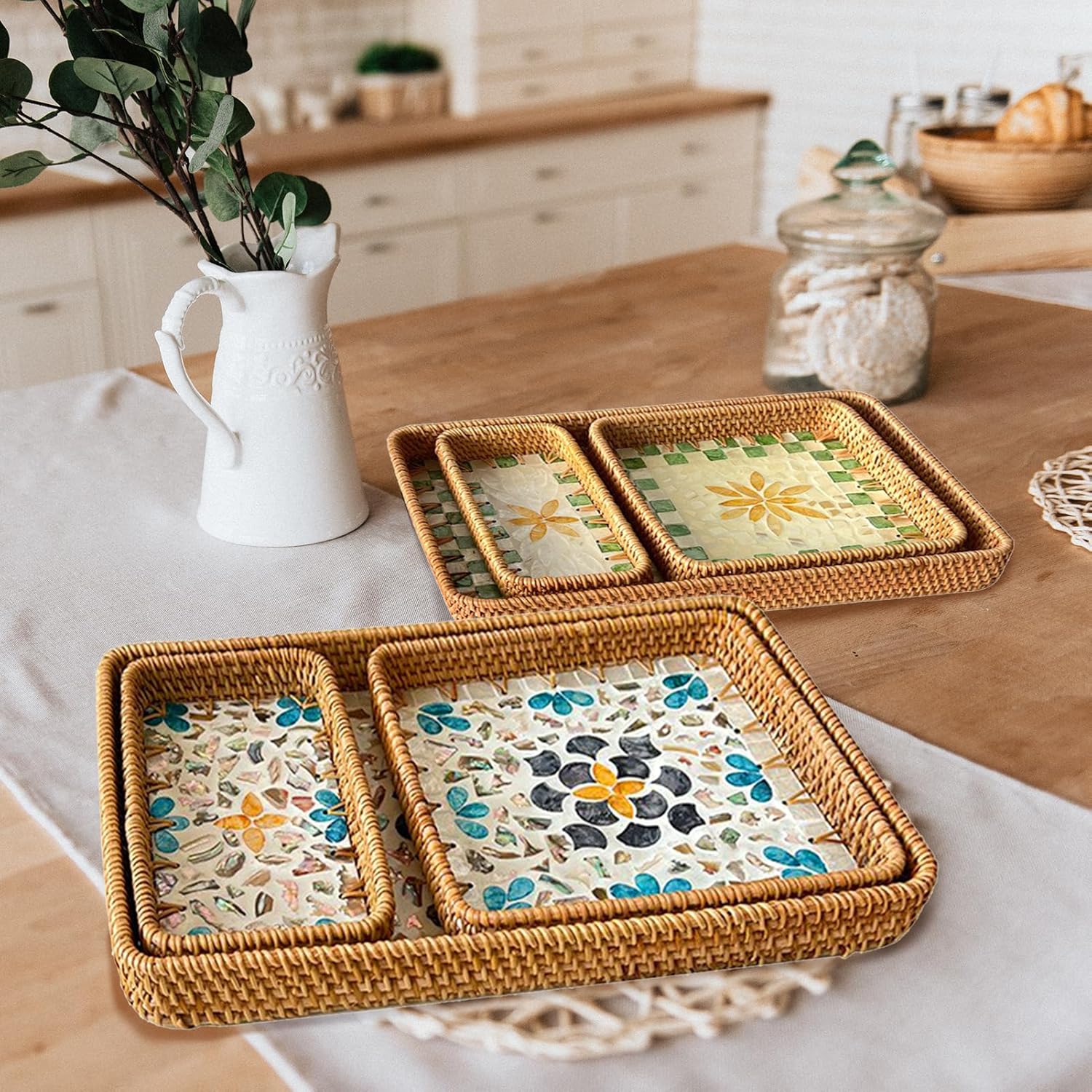 Rattan shell trays with colourful floral and leaf inlay arranged on a wooden table beside a white vase