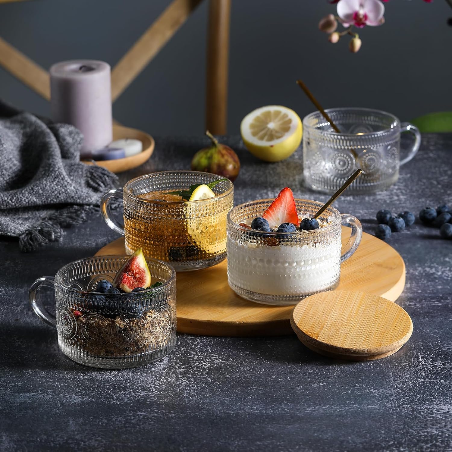 Embossed glass mugs arranged with fruit, yogurt and a drink beside a bamboo lid
