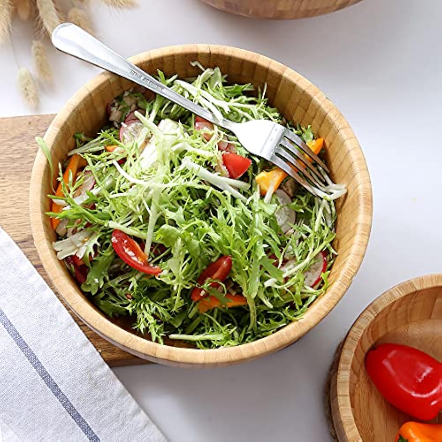 Round bamboo salad bowl filled with leafy greens and a fork resting across the rim