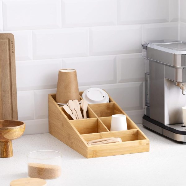 Bamboo coffee bar organizer on a kitchen counter with paper cups, cup lids, wooden spoons and wrapped drink supplies