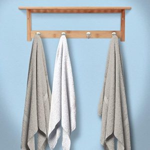Bamboo wall shelf mounted on a blue wall with three towels hanging from its four hooks