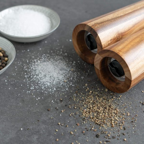 Close view of two acacia wood mill bases beside bowls of salt and peppercorns and freshly ground seasoning