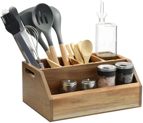Acacia wood countertop organizer holding kitchen utensils, an oil bottle and condiment jars