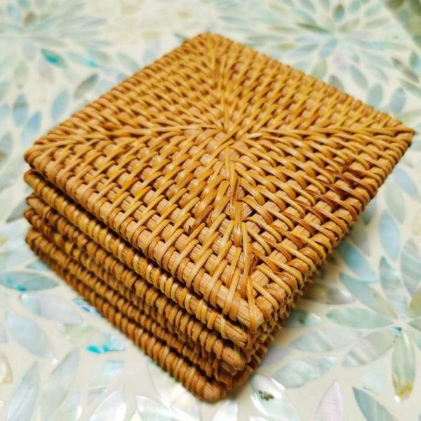 Close-up of stacked square rattan coasters showing the central weave pattern and bound edges