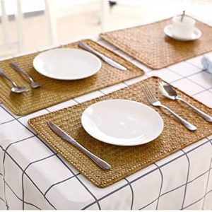 Rectangular seagrass woven placemats beneath white plates and a cup on a checked tablecloth