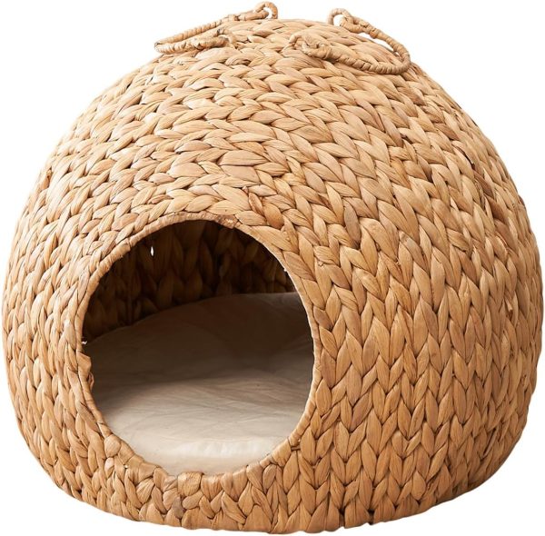 Front view of a woven water hyacinth cat cave with loop handles and a light-coloured pad visible inside