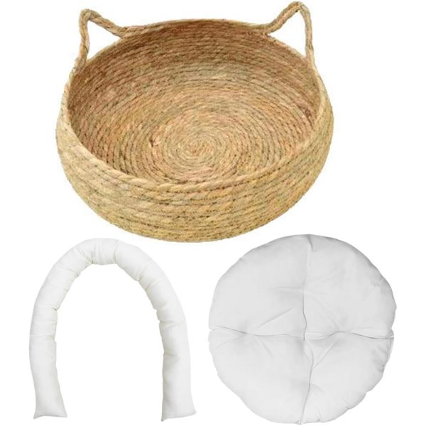 Empty round woven cat basket above a separate U-shaped bolster and circular white cushion