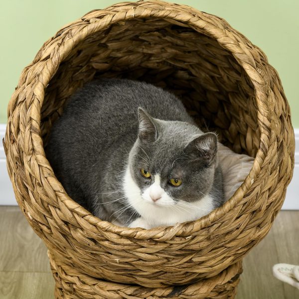 Close-up of an elevated cat bed with a grey and white cat inside the round woven basket