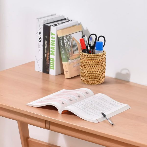 Rattan pen organizer holding pens and scissors on a wooden desk beside books and an open magazine