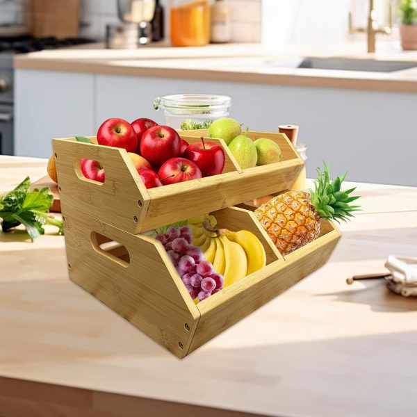 Two stacked bamboo produce bins holding apples, pears, grapes, bananas and a pineapple on a kitchen counter