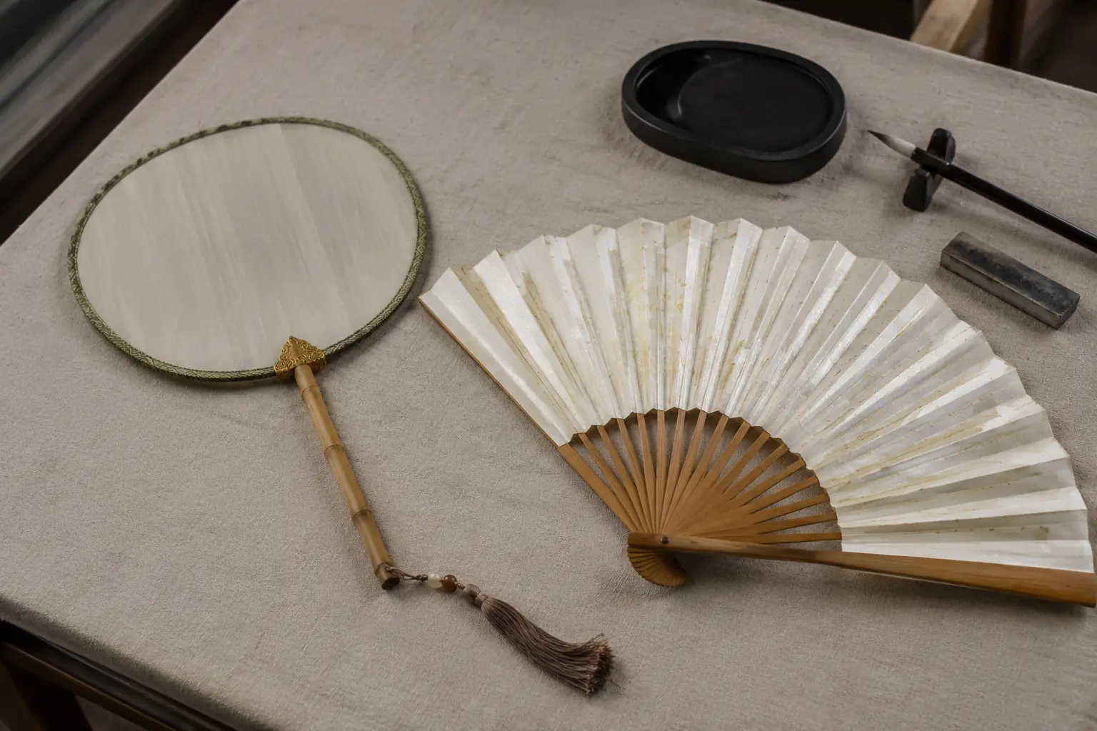 Leque chinês rígido redondo e leque dobrável de bambu sobre uma mesa